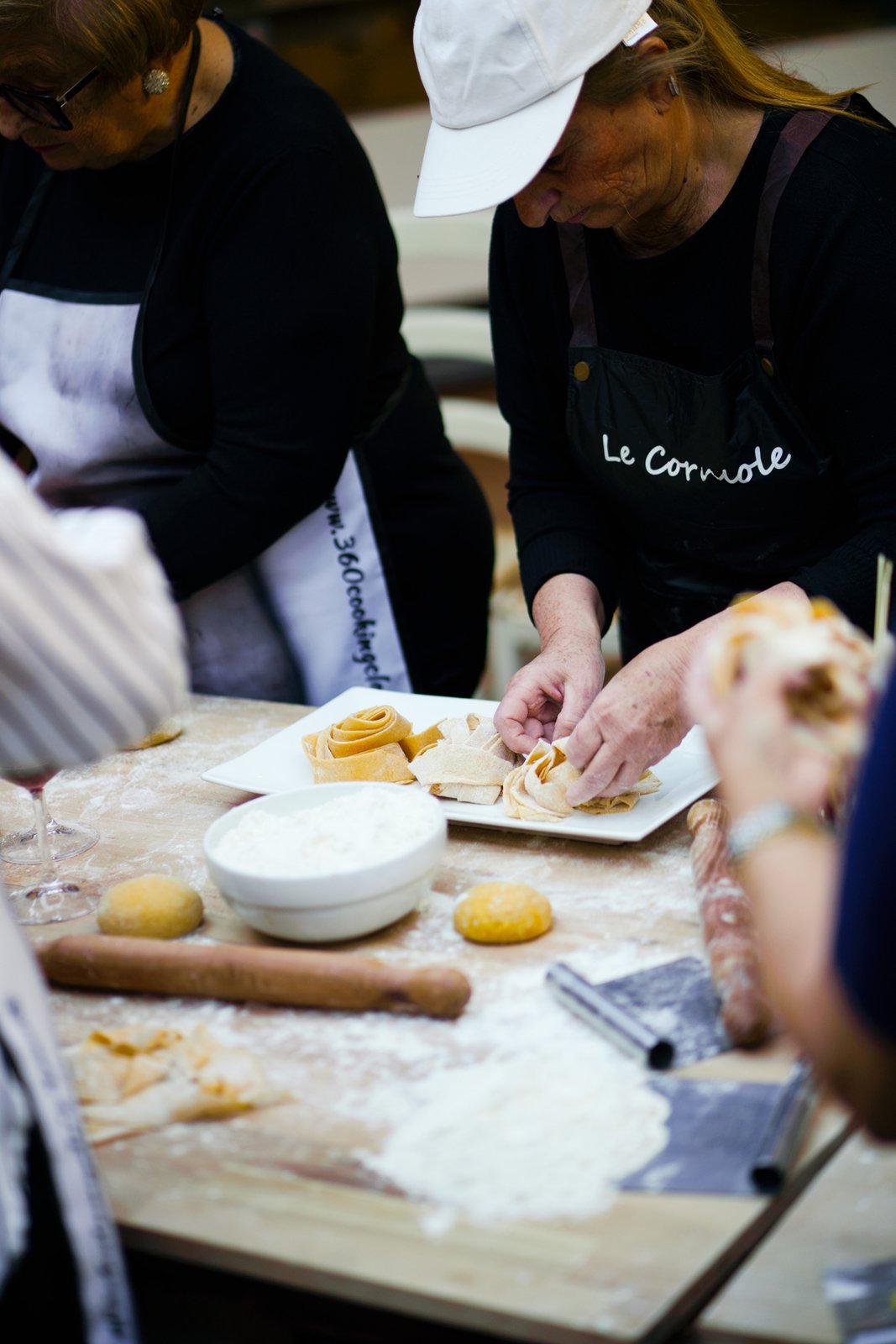 Guests in Le Corniole aprons making fresh pasta during the cooking class in Arezzo