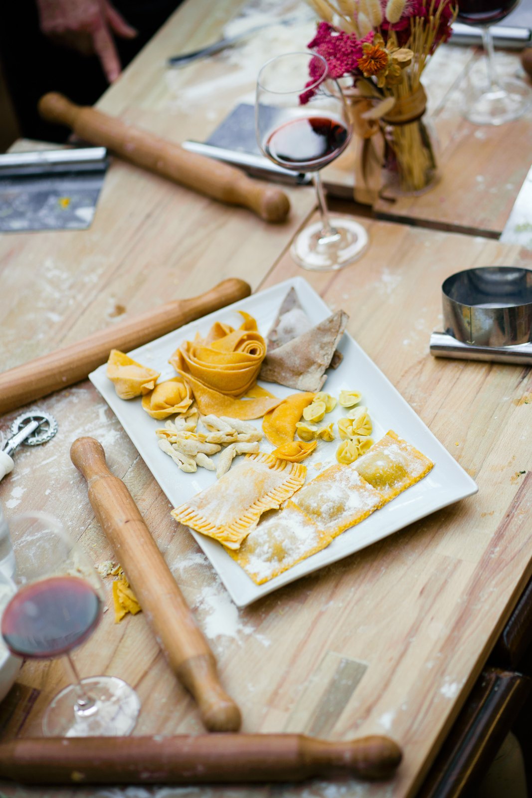 Fresh handmade pasta and ravioli on the class table with rolling pins and Tuscan wine